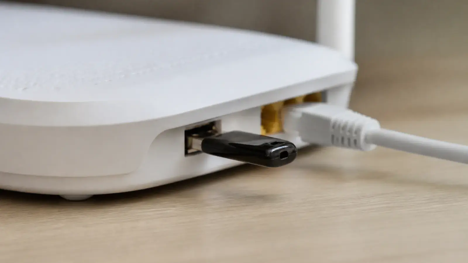 Крупный план белого роутера: чёрная флешка вставлена в USB-порт, рядом в сетевой порт подключён белый кабель