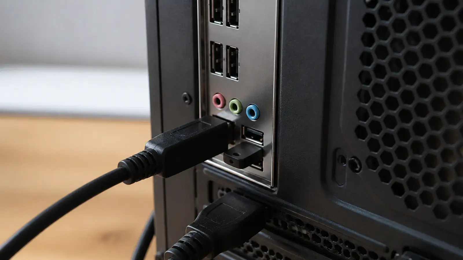 Крупный план: чёрный USB-токен вставлен в задний порт системного блока, рядом подключены кабели клавиатуры и монитора