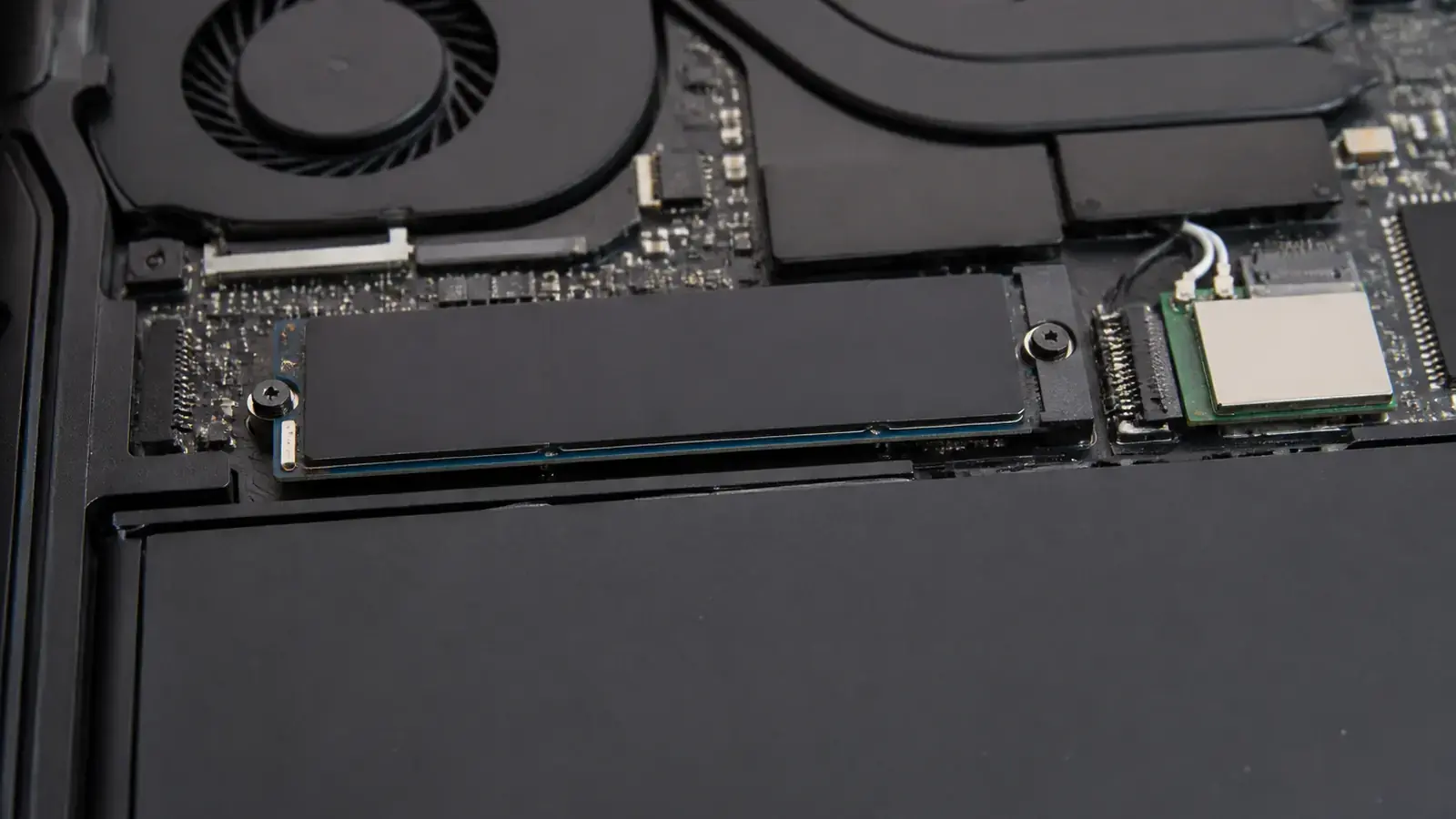 Внутри открытого ноутбука виден SSD формата M.2, закреплённый одним винтом рядом с модулем Wi-Fi и батареей, крупный план